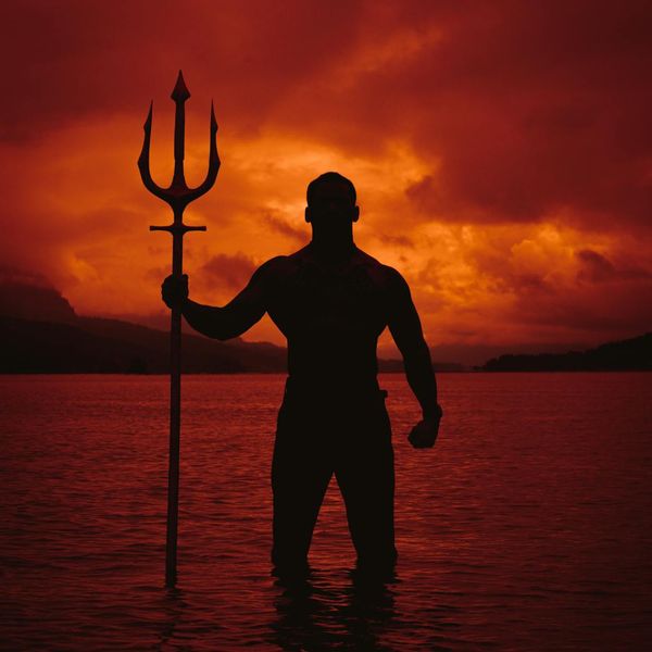Person holding a powerful warrior yoga pose outdoors at sunset.
